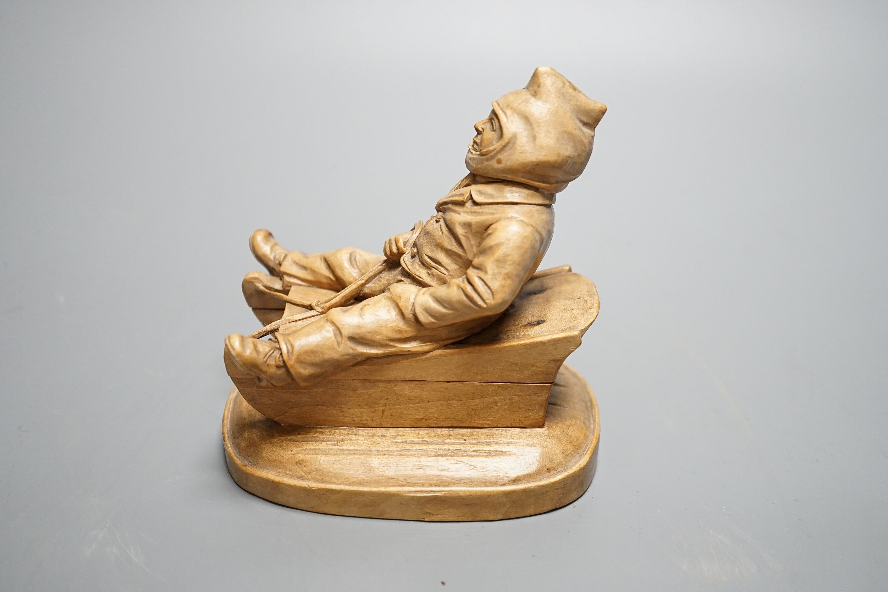 A North European novelty carved beech inkwell in the form of a seated figure sledging, c.1900, 11cm high, 11cm long.